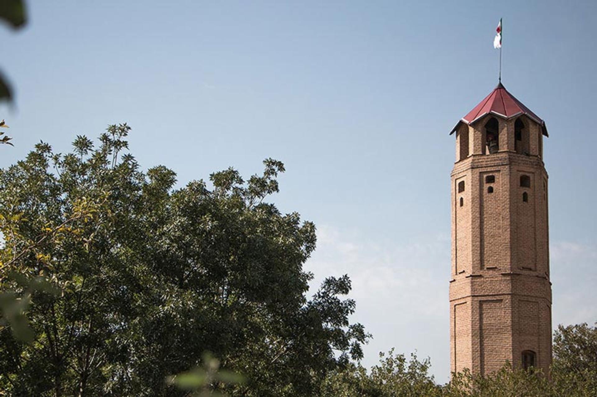 The lantern stage of the tower, its open arches under a red cap and flag against the sky
