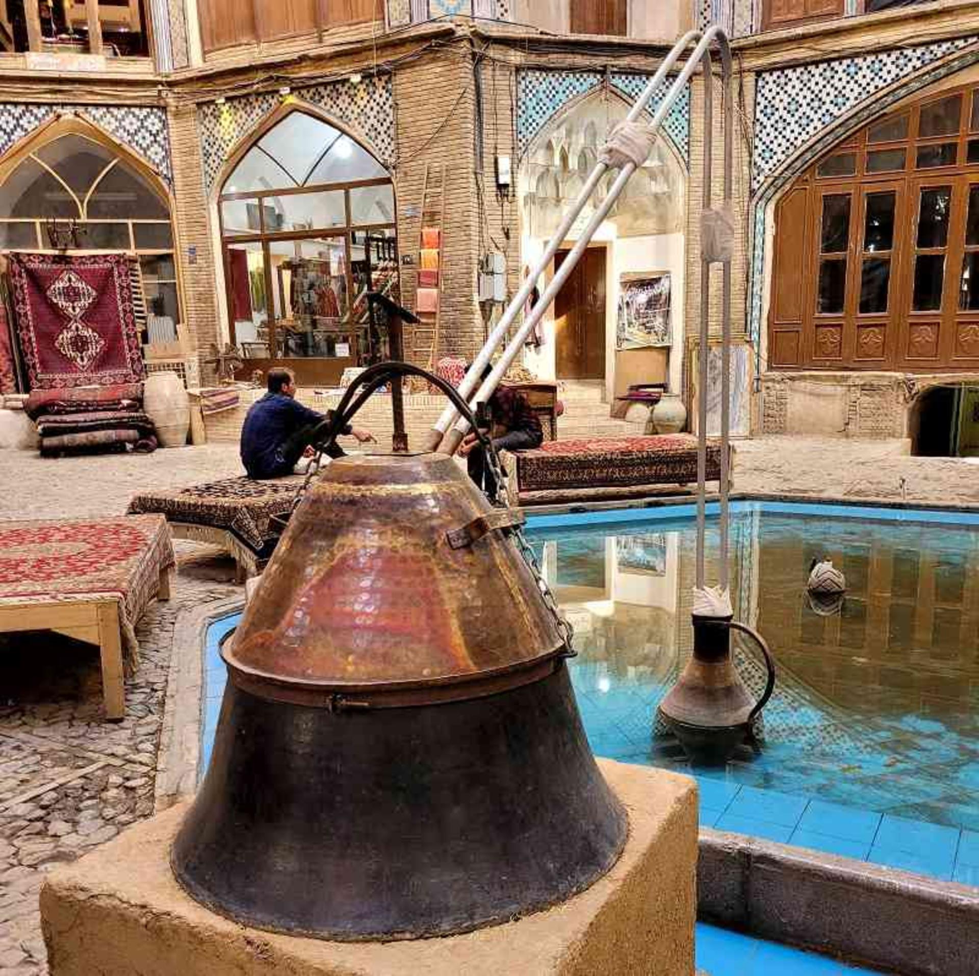 A copper rosewater still set up beside a courtyard pool in Kashan