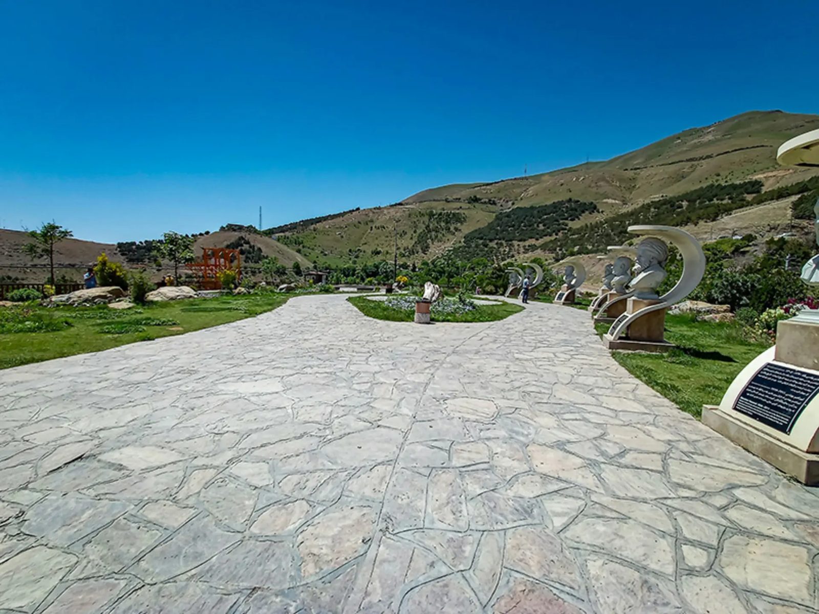 White bust sculptures in crescent-shaped frames along the stone-paved promenade of Abidar park in Sanandaj