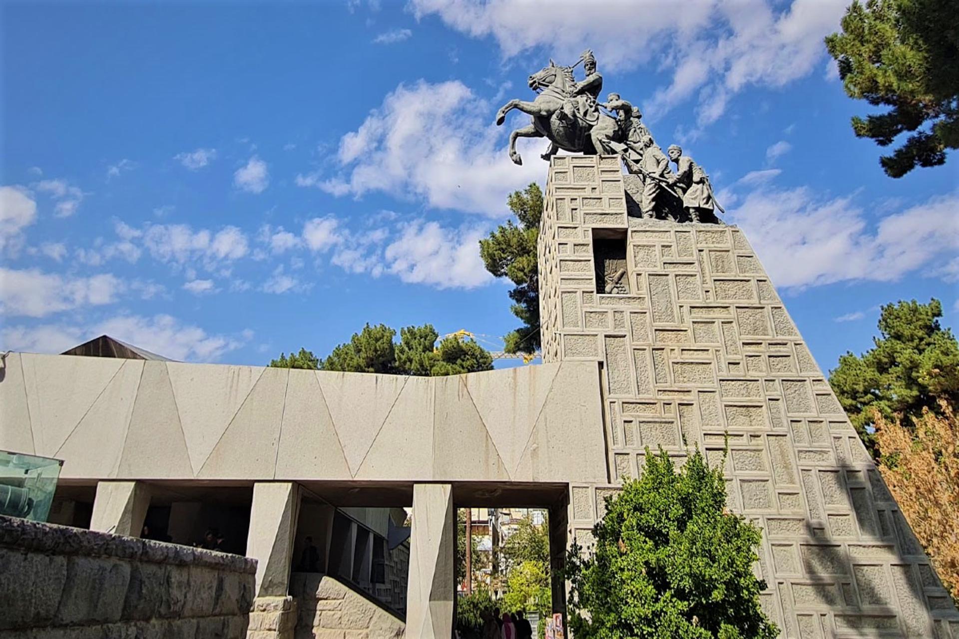 The Nader Shah monument in Mashhad, a bronze rider on a rearing horse above a stepped stone pedestal carved with soldiers