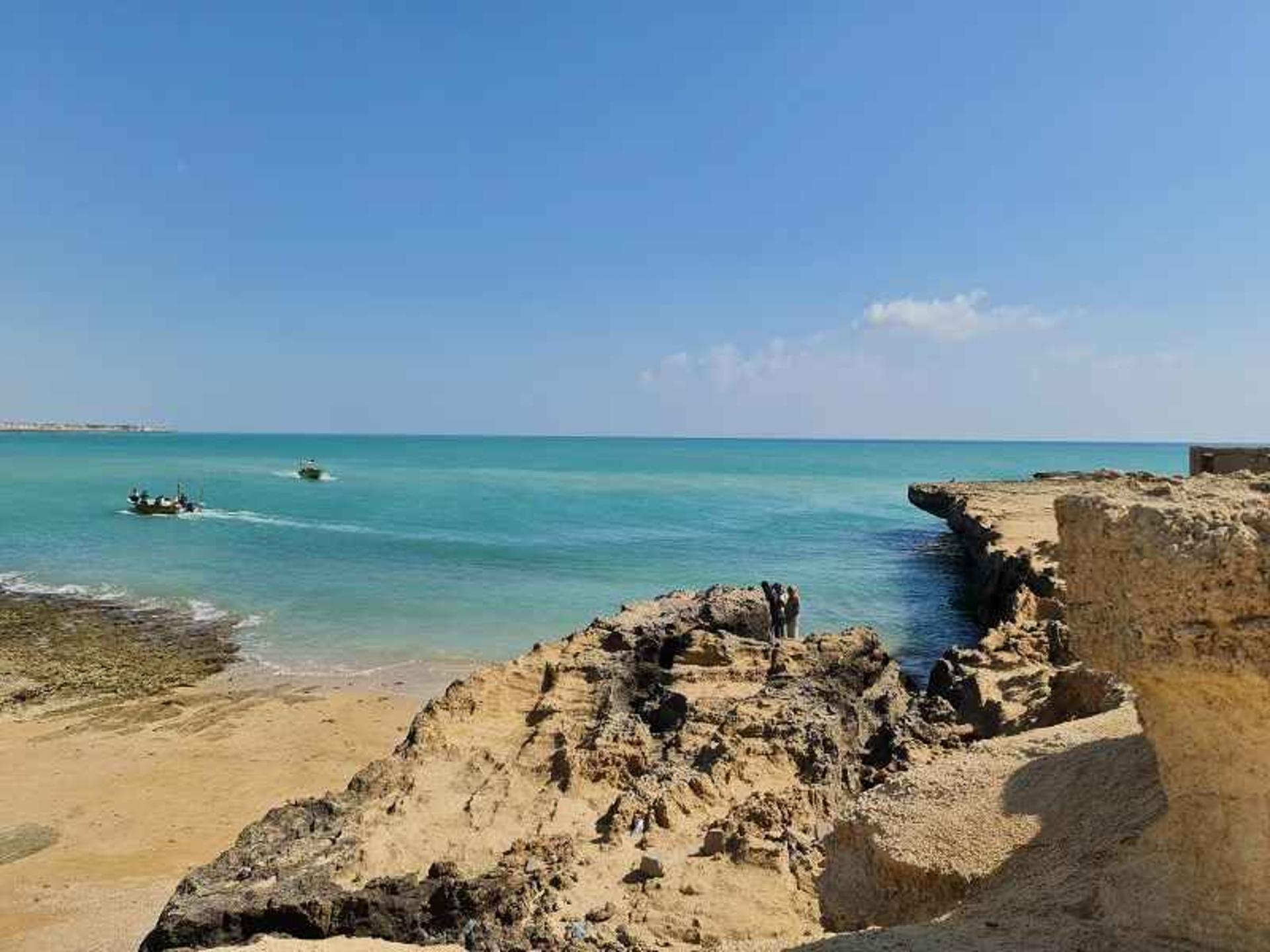 Motorboats cross the turquoise Persian Gulf water off Qeshm's rocky shore