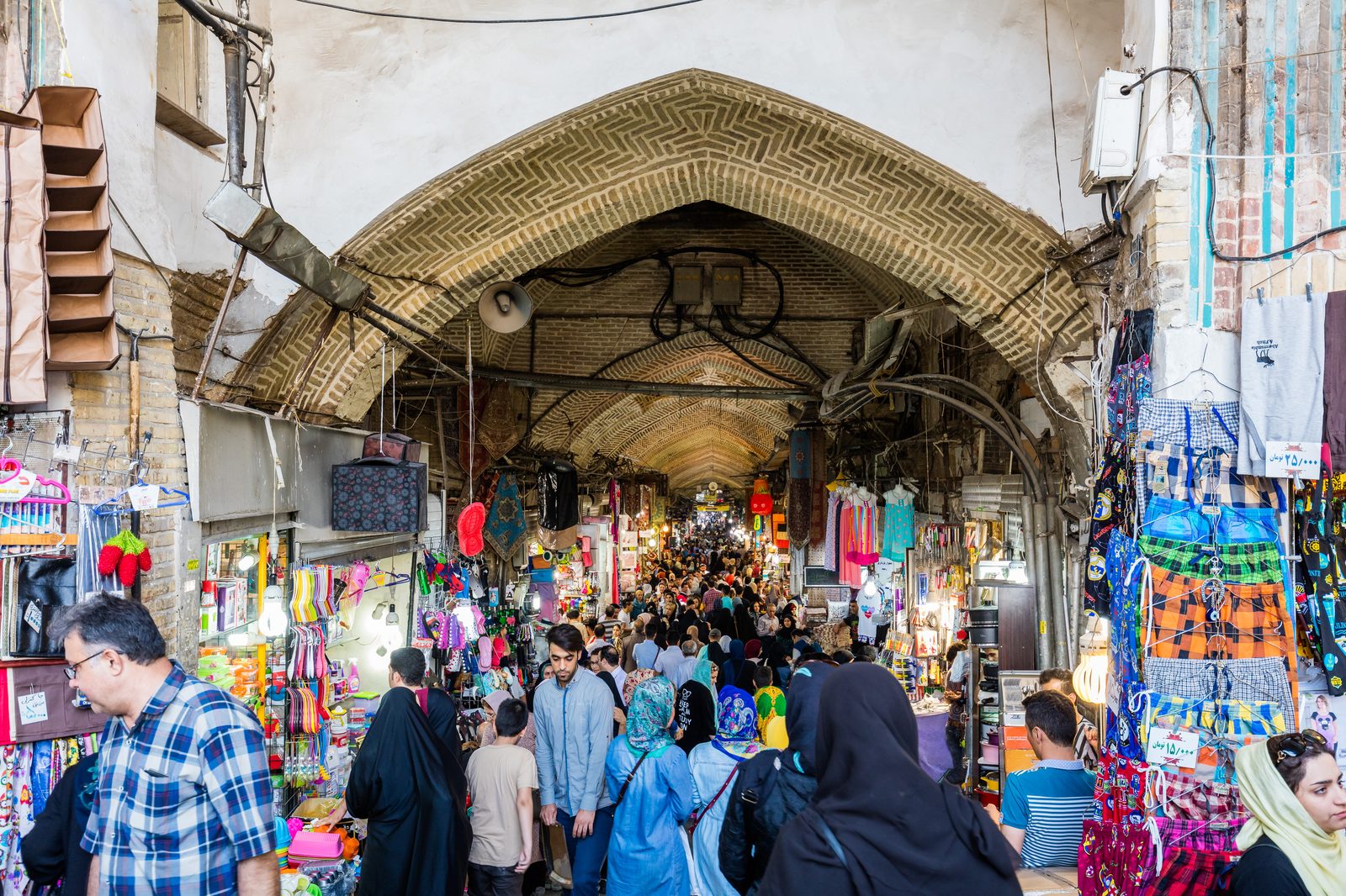 Rows of hand-knotted Persian carpets displayed in a traditional bazaar shop