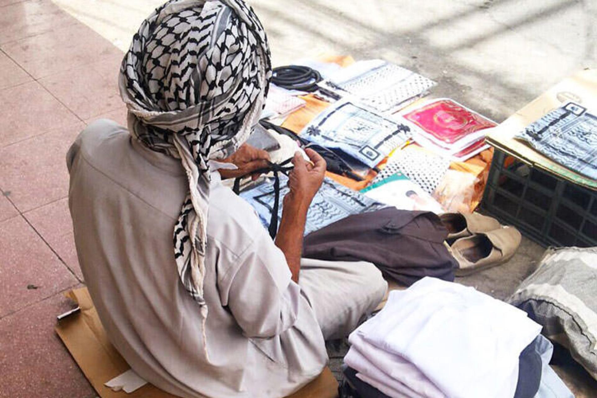 A merchant arranging headscarves and textiles at his stall