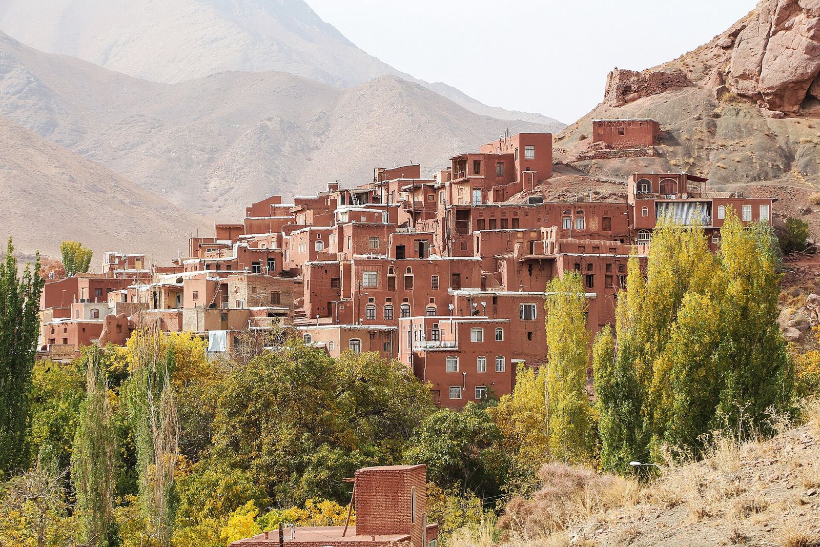 A narrow stone lane between red adobe houses in Abyaneh village
