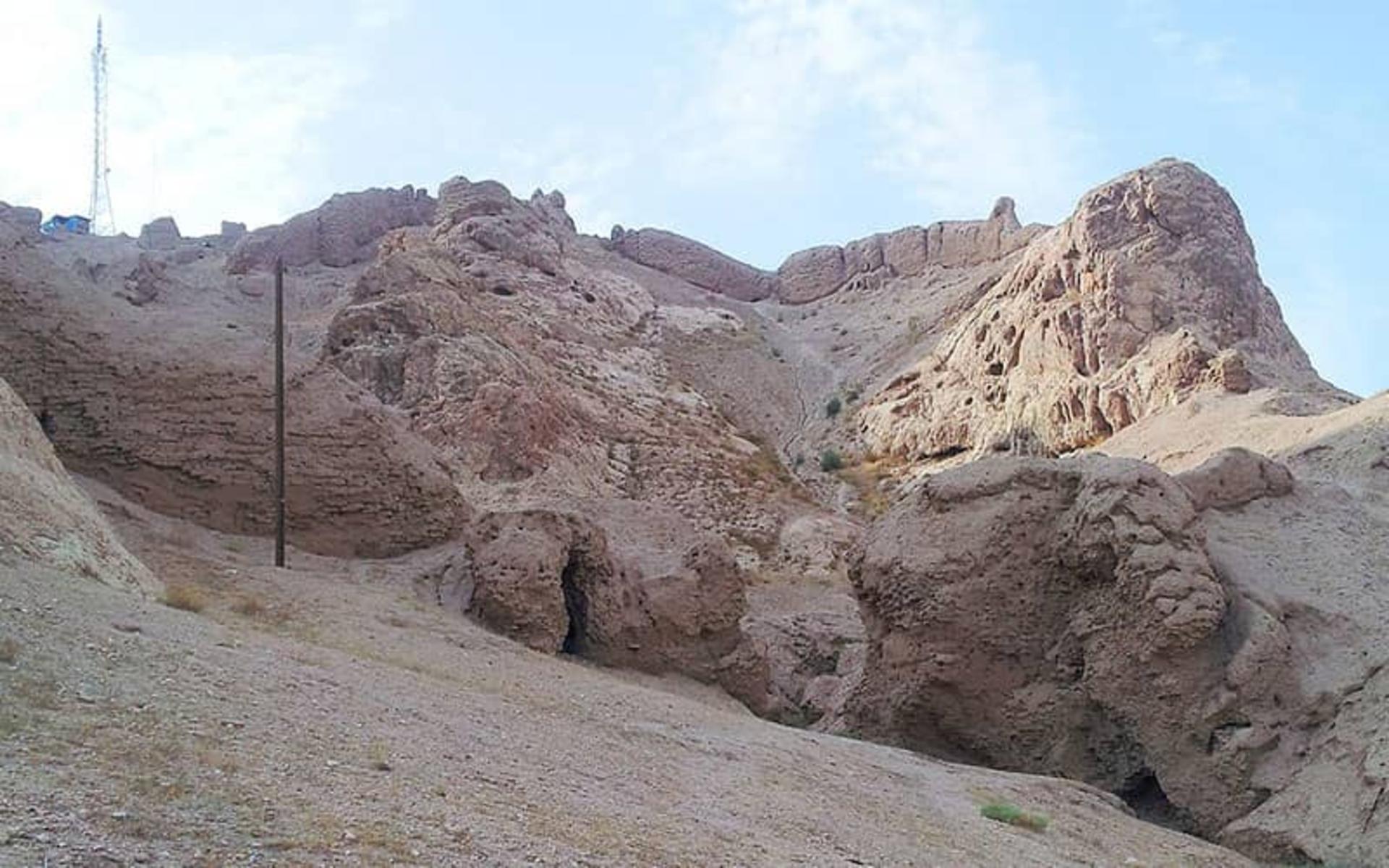 الطريق من أسفل، مجرى سيلٍ جافٍّ محفورٌ في المنحدرات اللبنية المتهالكة والقمةُ فوقه