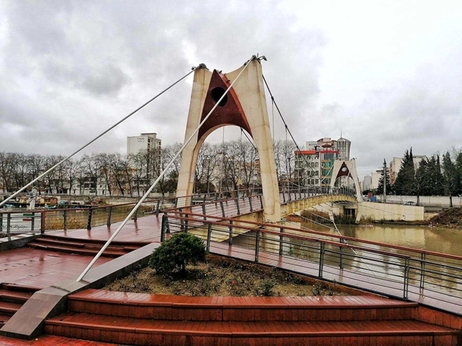 Modern pedestrian suspension bridge with cream A-frame pylons crossing the Babelrud