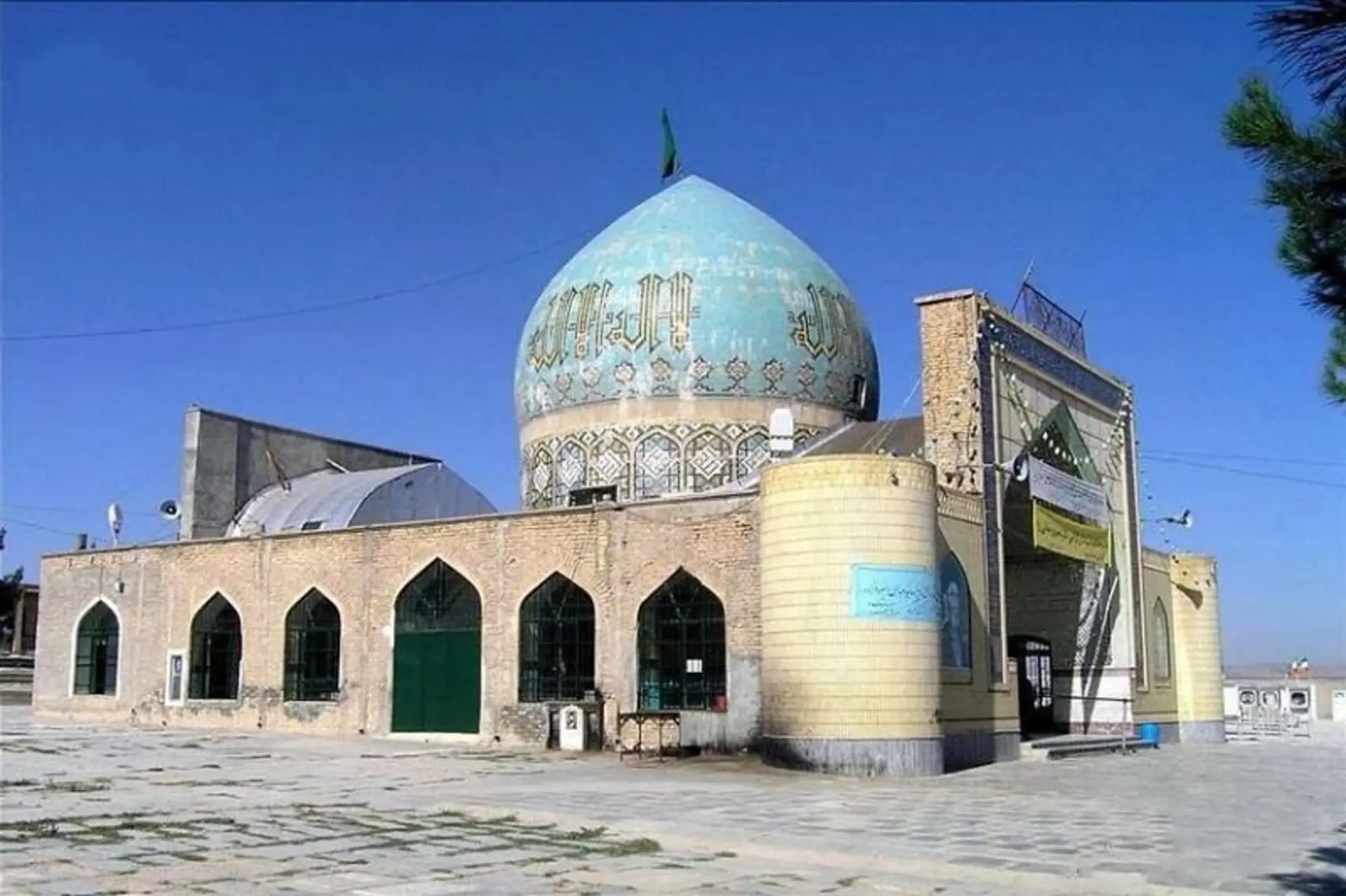 The turquoise dome and arched brick portico of Imamzadeh Sultan Seyyed Abbas above its paved court