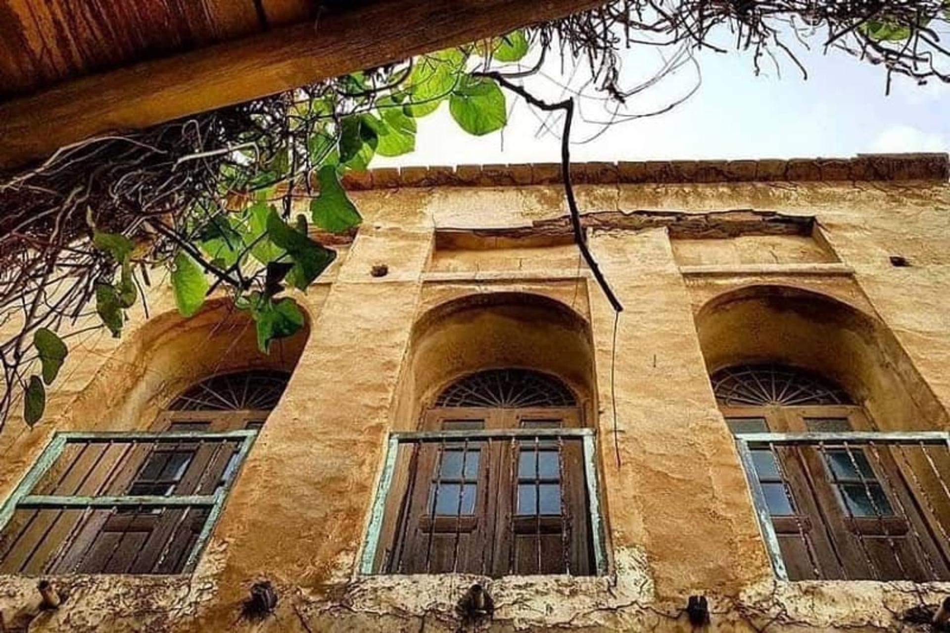 Wooden window shutters propped open inside deep arched recesses of a mudbrick house in old Bushehr