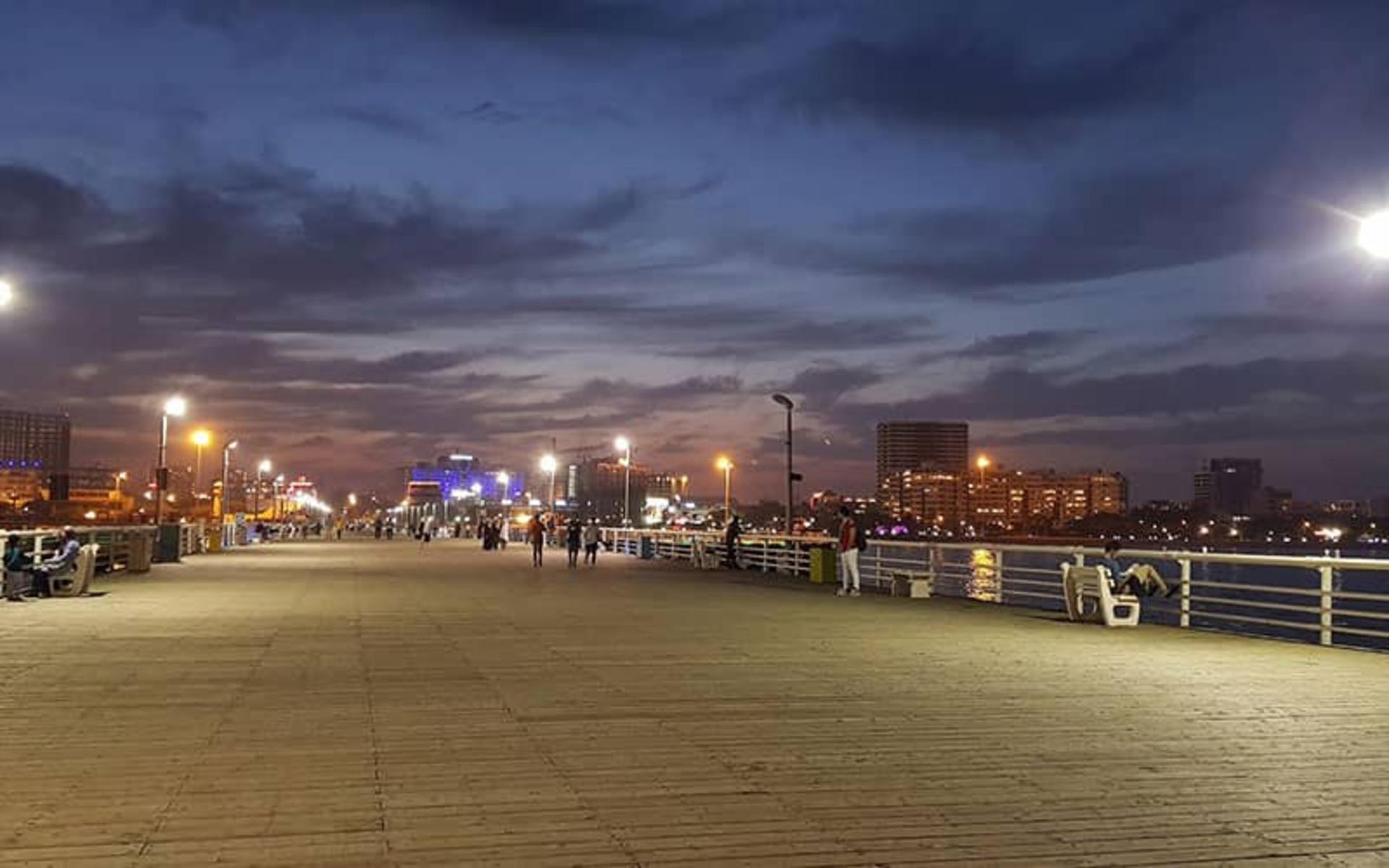 The Kish Recreational Pier at dusk, its lamps and white benches above the water