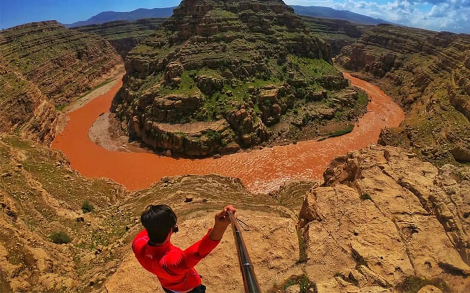 A red-rock horseshoe bend carved by a river through a deep gorge, seen from the rim at Khazineh