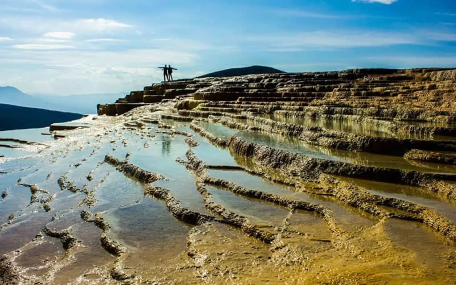 The stepped spring pools of Badab-e Surt, orange and rust from iron sediment