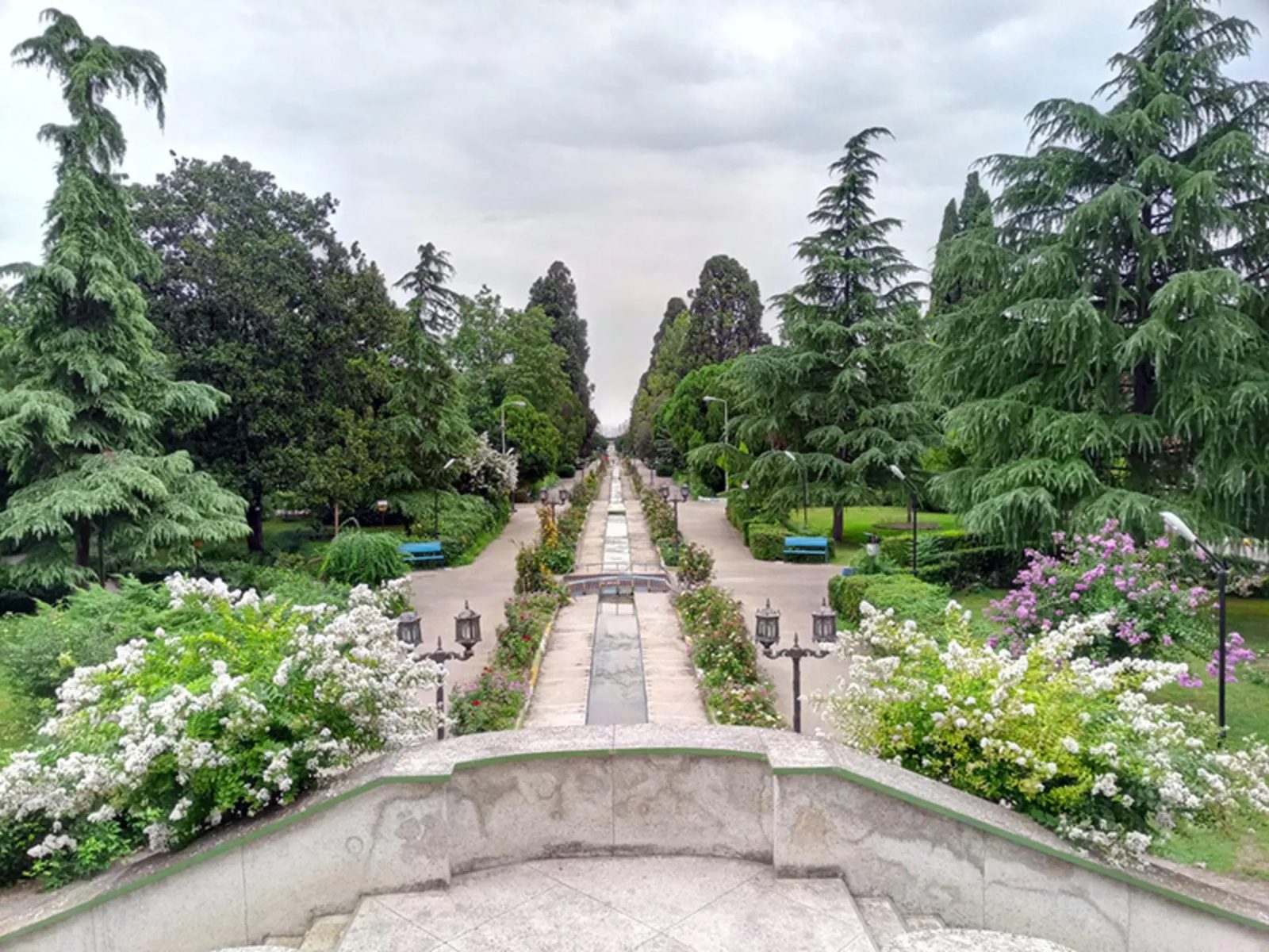 A long formal water channel lined with benches and flowering shrubs